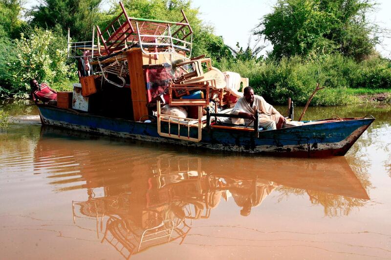 Sudanese men transport their belongings on a boat during flash floods in Wad Ramli village on the eastern banks of the Nile river.  AFP