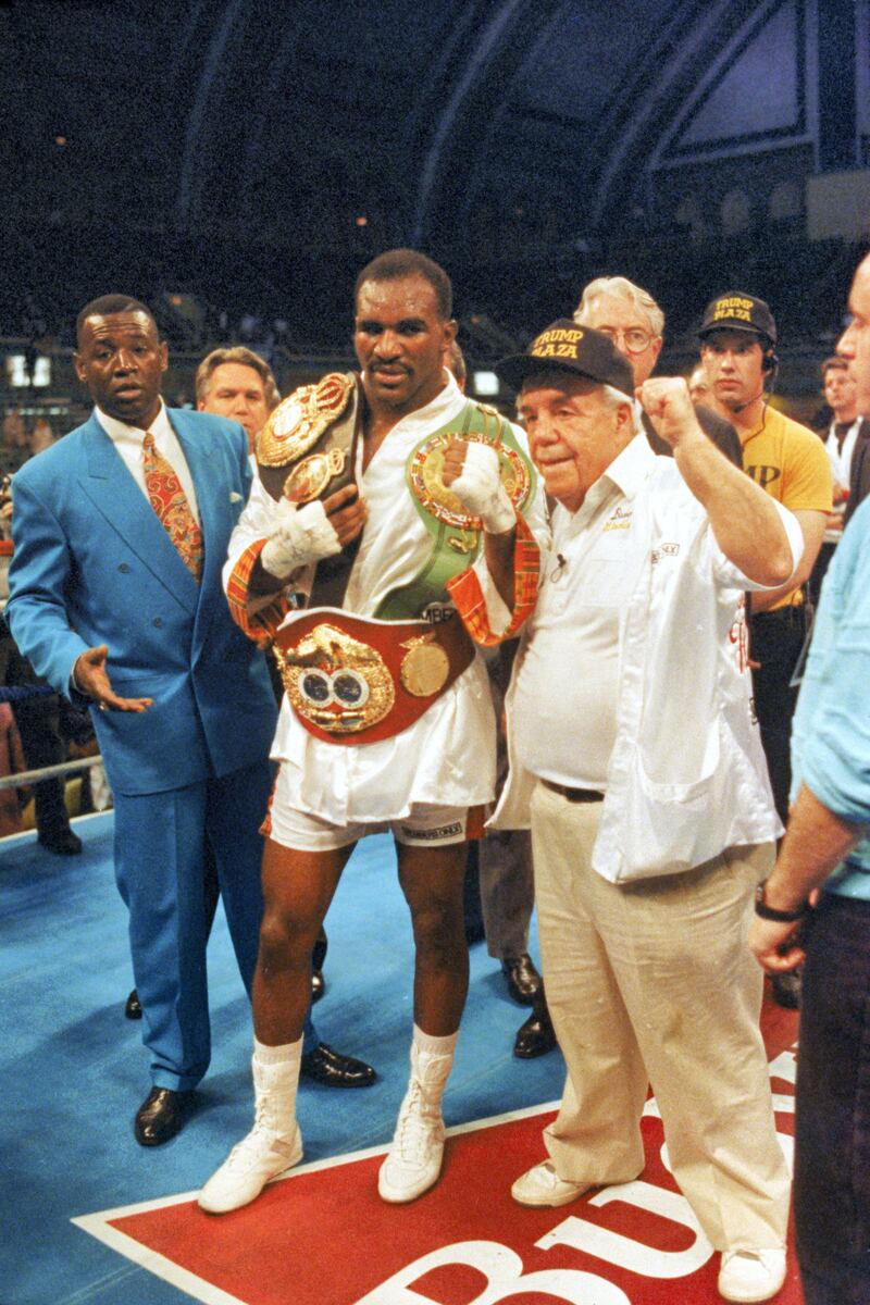 ATLANTIC CITY, NJ - APRIL 19:  Evander Holyfield poses for a photo with his WBC, WBA, IBF Heavyweight championship Title belts after defeating George Foreman in a twelve round bout at the Trump Plaza Convention Center on April 19, 1991 in Atlantic City, New Jersey.  Holyfield defeated Foreman in a unanimous decision and retained the undisputed heavyweight Title.  (Photo by Andrew D. Bernstein/Getty Images)