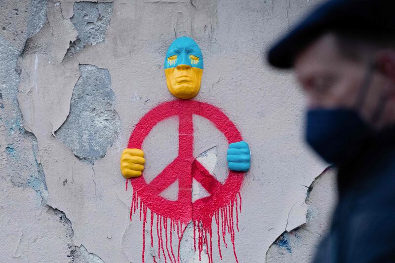An installation by street artist Gregos representing a face in the colors of Ukraine's flag and holding a symbol of peace, in Paris. AFP