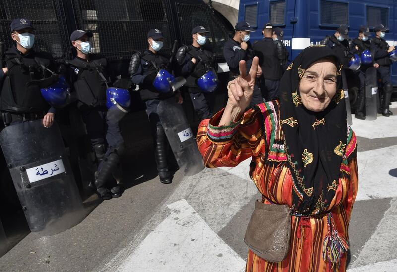 An Algerian protester in traditional Amazigh (Berber) attire flashes the sign of fictory in front of a cordon of anti-riot police during the weekly anti-government demonstration in the capital Algiers.  AFP