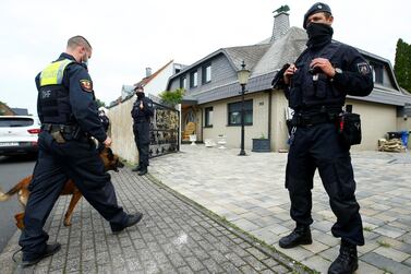 A German police officer and a sniffer dog enter the yard of a villa after a police raid in Leverkusen, Germany. Reuters