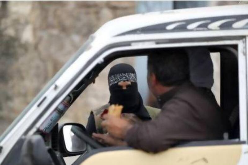 A female member of the Al Ikhlas (loyalty) battalion, stops a van at a checkpoint in Aleppo. The battalion is under the Ghorabaa (strangers) Al Sham Front, controlled by the Free Syrian Army.