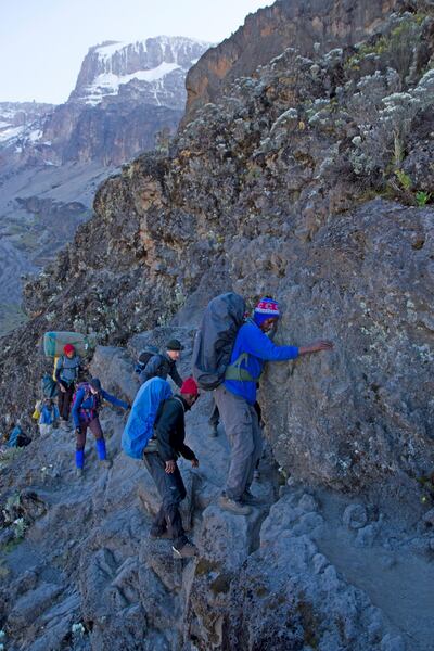 Mt Kilimanjaro National Park, Tanzania, July 1 2017: A group of trekkers inches around the so-called Kissing Rock on the tricky Barranco Wall section of trail on Mt Kilimanjaro. Getty Images