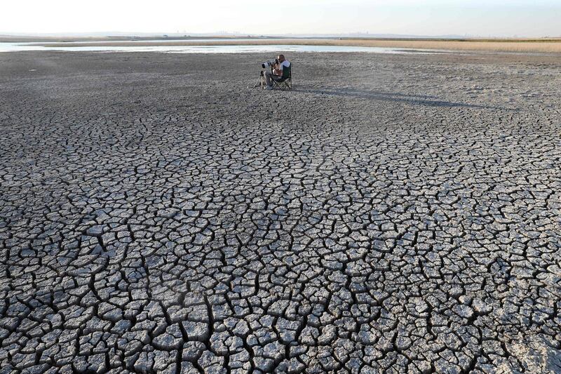 A photographer takes pictures of the cracked soil after a drought at Dikilitas Pond in the Golbasi district of Ankara.  AFP