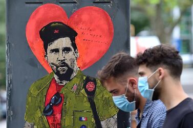 People walk past a new artwork by street artist TVBoy depicting Barcelona's Argentinian forward Lionel Messi entitled "Hasta Siempre Comandante" (Until Forever, Commander) in Barcelona on August 29, 2020. Messi has provoked a football frenzy by announcing he wants to leave Barcelona, the club he joined as a 13-year-old in 2000 and has led to four Champions League titles. - RESTRICTED TO EDITORIAL USE - MANDATORY MENTION OF THE ARTIST UPON PUBLICATION - TO ILLUSTRATE THE EVENT AS SPECIFIED IN THE CAPTION / AFP / Pau BARRENA / RESTRICTED TO EDITORIAL USE - MANDATORY MENTION OF THE ARTIST UPON PUBLICATION - TO ILLUSTRATE THE EVENT AS SPECIFIED IN THE CAPTION