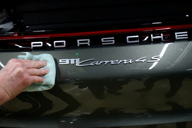 An employee fixes a Porsche 911 Carrera 4S label, at the car maker's factory in Germany. Reuters