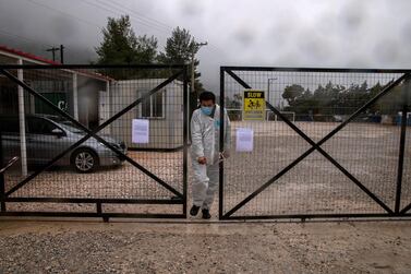 A man wearing a protective suit and a face mask exits the Malakasa migrant camp after authorities found a coronavirus case, April 5, 2020. Reuters