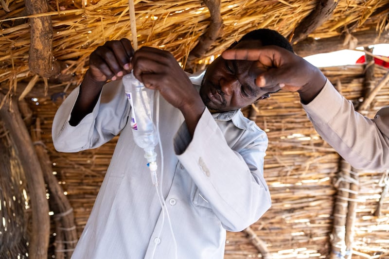 Thirty-six-year-old doctor and Sudanese refugee Yassin Ishag Dawod gets an intravenous drip ready while attending a patient in the Farchana refugee camp