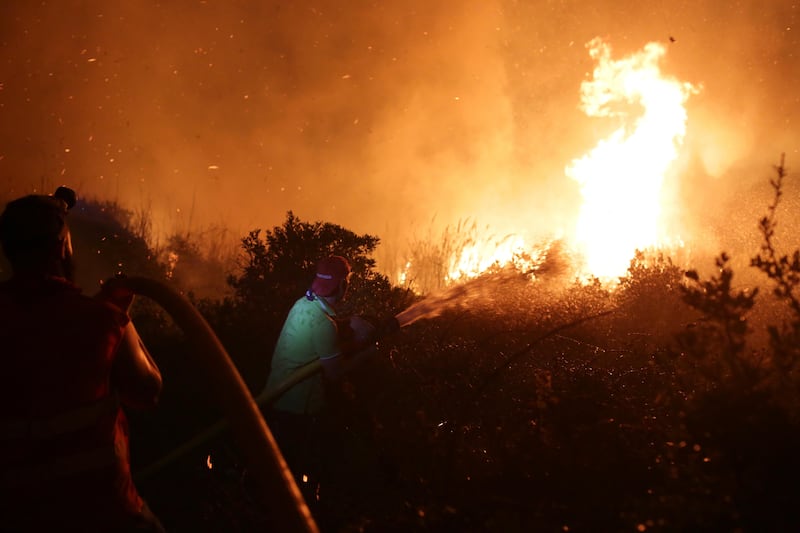 Firefighters and volunteers battle a wild fire raging near houses in the outskirts of Obidos, Portugal. Armando Franca / AP Photo