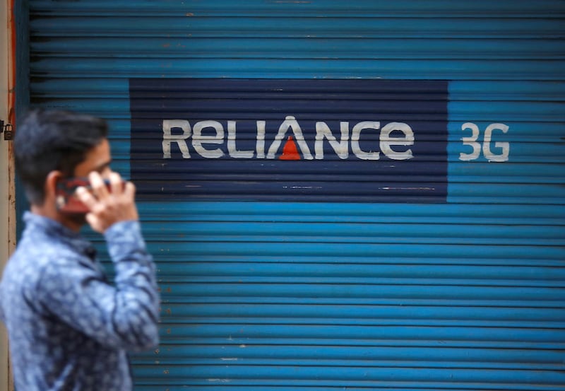 FILE PHOTO: A man speaks on his mobile phone as he walks past a closed shop painted with an advertisement of Reliance Communications in Mumbai, India, January 29, 2018. REUTERS/Shailesh Andrade/File Photo