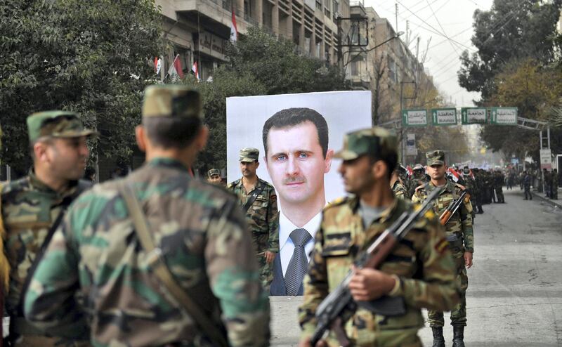 Syrian soldiers walk past a portrait of President Bashar al-Assad during a government celebration marking the first anniversary of the retaking of the northern Syrian city of Aleppo, near the square of Saadallah al-Jabiri on December 21, 2017.
After a suffocating siege and a crushing offensive which used barrel bombs, rockets and shells, the Syrian army declared in December 2016 it had full control of second city Aleppo. / AFP PHOTO / George OURFALIAN