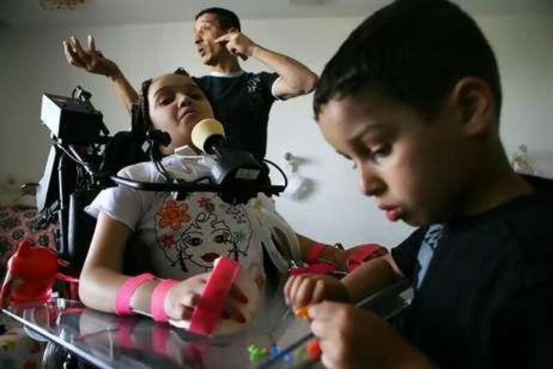 Maria Aman, who is paralysed from her neck down, sits in her hospital room with her younger brother Moman and her father Hamdi, in Jerusalem.