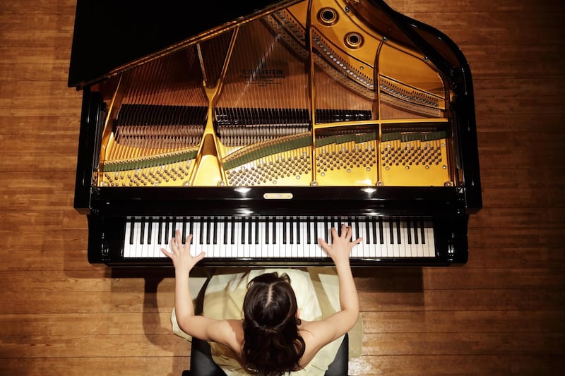 Female pianist playing grand piano at concert hall stage. Getty Images