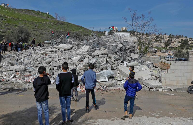 Palestinians stand by the rubble of buildings demolished by Jerusalem municipality workers, reportedly built without an Israeli construction permit, in the mostly-Arab east Jerusalem neighbourhood of Issawiya on February 22, 2021. / AFP / AHMAD GHARABLI
