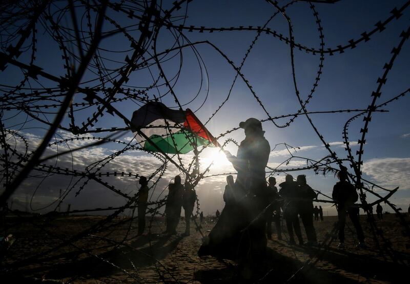 Palestinian protesters wave a national flag near concertina wire at the Israel-Gaza border, east of Rafah in the southern Gaza Strip. AFP
