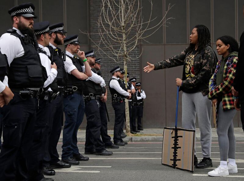 A protester reaches out to greet a police officer near the US embassy in London. AP