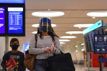 Passengers of an Emirates airlines flight, departing to the Australian city of Sydney, wear protective gear at Dubai International Airport on May 22, 2020, after the resumption of scheduled operations by the Emirati carrier, amid the ongoing novel coronavirus pandemic crisis. / AFP / Karim SAHIB