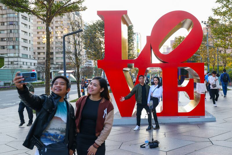 People enjoy posing for photos next to a giant 'LOVE' sign installation during the celebration of Valentine's day in Taipei, Taiwan, 14 February 2024.  People all over the world celebrate Valentine's Day annually on 14 February by giving flowers, chocolates, or cards to loved ones.   EPA/RITCHIE B.  TONGO