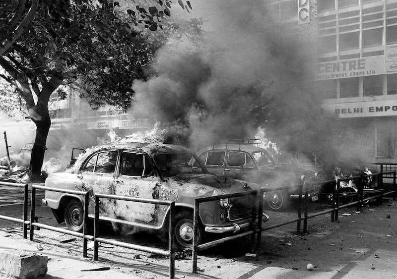 A fleet of Sikh owned cars burn and are covered in thick black smoke after they have been set on fire by rioting Hindus in downtown New Delhi, Nov. 1, 1984 near the Parliament Square. Violence all over the country and in the capital broke out following the killing of Prime Minister Indira Gandi. (AP Photo/Peter Kemp)