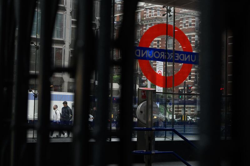 Commuters walk past a locked Tube station entrance in London. Getty Images