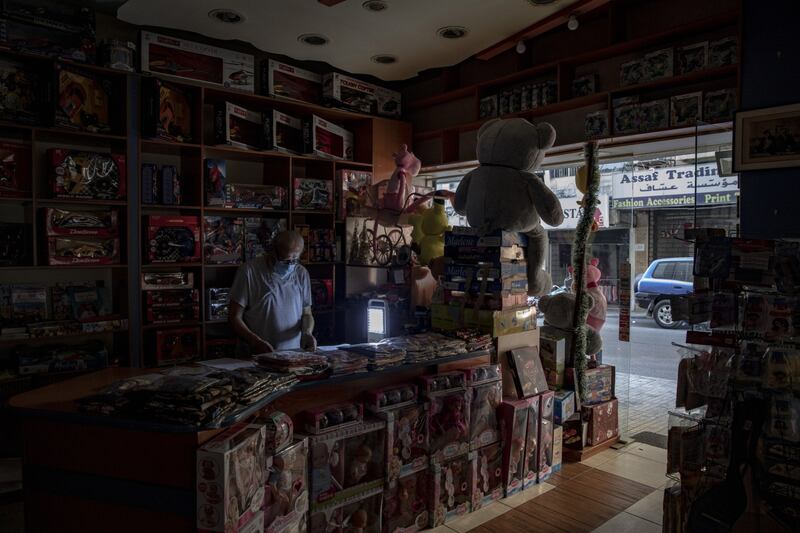 A man uses a portable lamp inside his toy shop during a power cut in Beirut, Lebanon. All Photos: Bloomberg