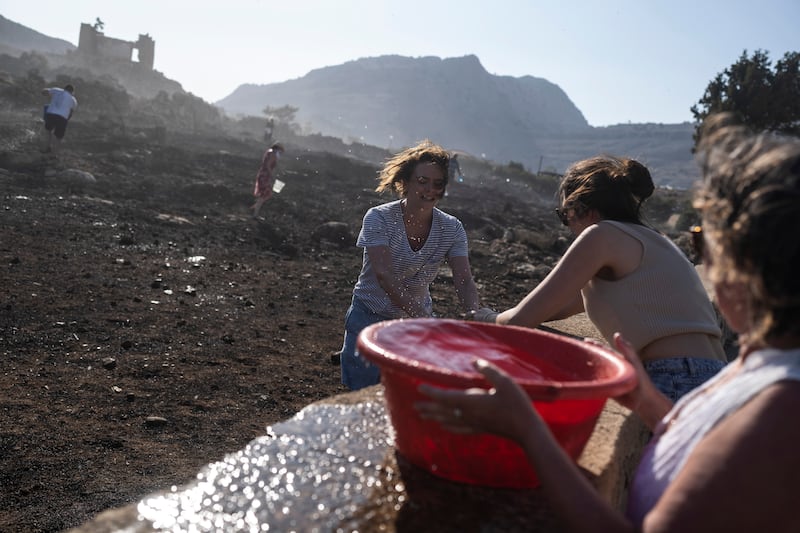 German tourists and local residents try to extinguish a fire near the seaside resort of Lindos. AP