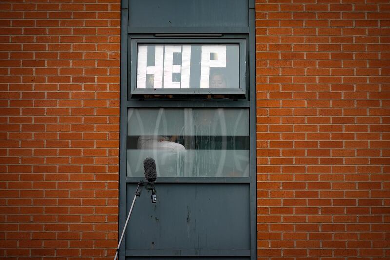 MANCHESTER, ENGLAND - SEPTEMBER 28: Isolating students peer out of their accommodation window as they are interviewed by a television crew on September 28, 2020 in Manchester, England. Around 1,700 students across two student housing blocks were told to self-isolate after more than 100 students recently tested positive for Covid-19. The students were told to self-isolate for 14 days even if they were not experiencing symptoms. (Photo by Christopher Furlong/Getty Images)