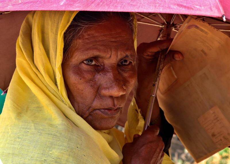 A Rohingya refugee woman holds an umbrella as she waits to collect food aid at the Kutupalong refugee camp in Cox's Bazar, Bangladesh. AP