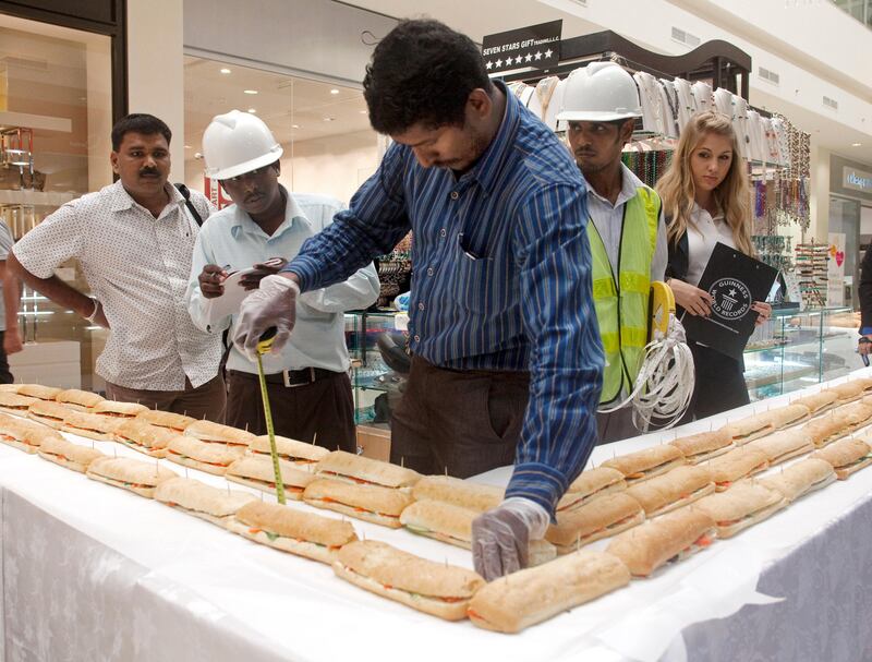 Dubai, October 7, 2010 - Noushad, a survey manager with Falcon Survey Engineering Consultancy, double checks the measurement of a section of what is the world's longest sandwich made at Dubai Outlet Mall in Dubai, October 7, 2010. Liz Smith (R) of Guinness World Records, oversees the measuring and later verified the sandwich is 2,667.13 meters long. The sandwich sections will be distributed to laborers in three different camps and some families in Dubai. (Jeff Topping/The National) 