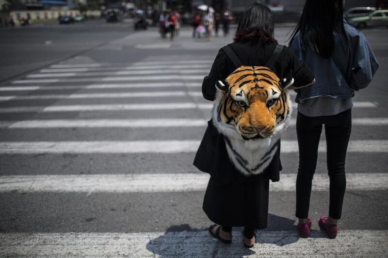 A woman waits at an intersection while carrying a tiger head backpack in Shanghai. Aly Song / Reuters / May 2, 2014