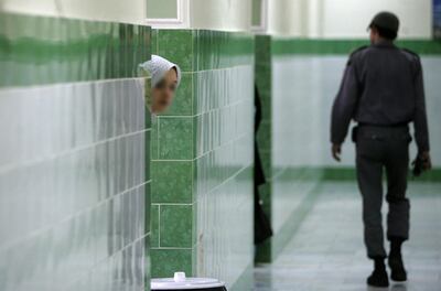 (FILES) In this file photo taken on June 13, 2006 an Iranian inmate peers from behind a wall as a guard walks by at the female section of the infamous Evin jail, north of Tehran. Two Australians detained in Iran were named on September 12, 2019 as a travel-blogging couple who were arrested while making an overland trip from their home country to Britain. Perth-based Jolie King and Mark Firkin had been documenting their journey on social media for the past two years but went silent after posting updates from Kyrgyzstan and Pakistan about 10 weeks ago.
 / AFP / ATTA KENARE
