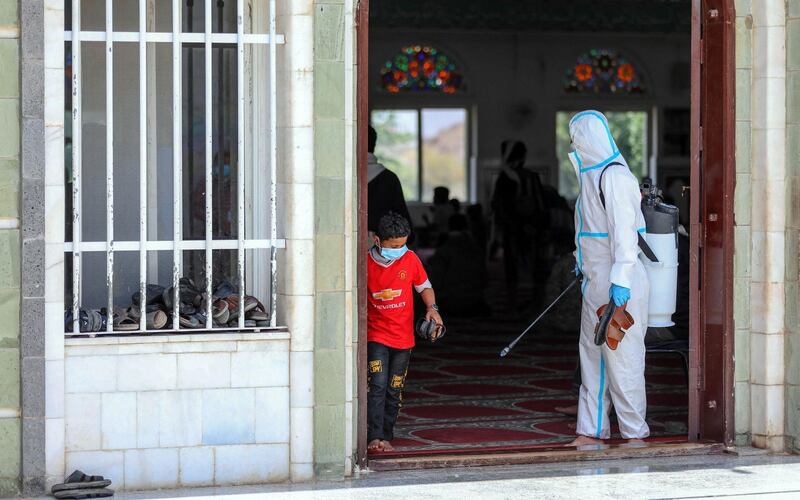 A worker sprays disinfectant as people gather for noon prayers inside a mosque in the Yemeni city of Taez. AFP