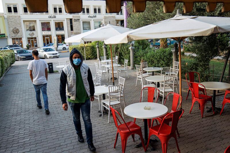 A man, mask-clad due to the COVID-19 coronavirus pandemic, walks past empty tables at a cafe in Libya's eastern city of Benghazi.  AFP