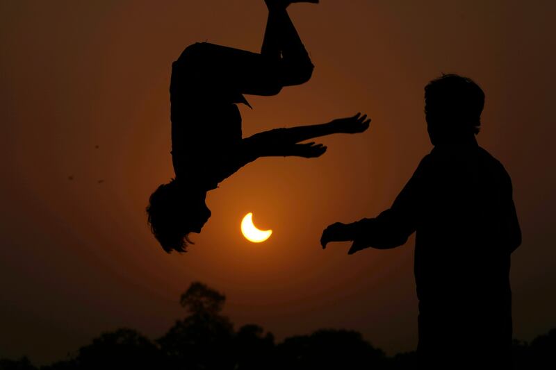 The partial solar eclipse is framed by youngsters jumping on a trampoline in the outskirts of Lahore, Pakistan. AP
