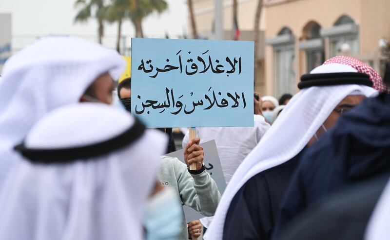 This Kuwaiti demonstrator's placard reads 'Closure ends in bankruptcy and jail'. All businesses, including malls, must close between the hours of 8pm and 5am.  EPA