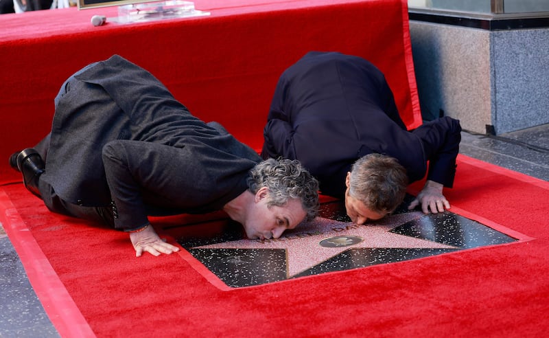 US actors Mark Ruffalo, left, and Willem Dafoe kiss Dafoe's newly unveiled star, during the ceremony honoring him with a Hollywood Walk of Fame star, in Hollywood. AFP