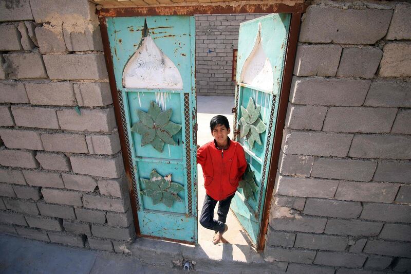An Iraqi boys stands in the doorway of a house in al-Zubair, south of Basra, on February 11, 2018. 
Informal housing settlements are flourishing in the oil-rich province of Basra, as Iraqis who have failed to find work in the energy industry and internal refugees struggle to find affordable housing.

 / AFP PHOTO / HAIDAR MOHAMMED ALI