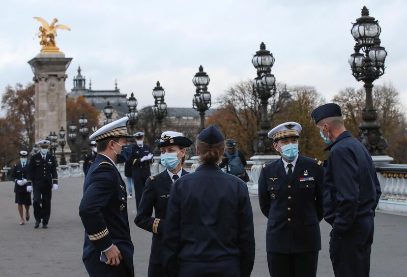 French army officers wearing face masks as a precaution against the coronavirus gather at Alexander III bridge after a military ceremony in Paris. France's health minister says the country is "progressively getting back in control" of its resurgent coronavirus epidemic but warns that it will quickly flare again if people start ignoring lockdown rules. AP Photo