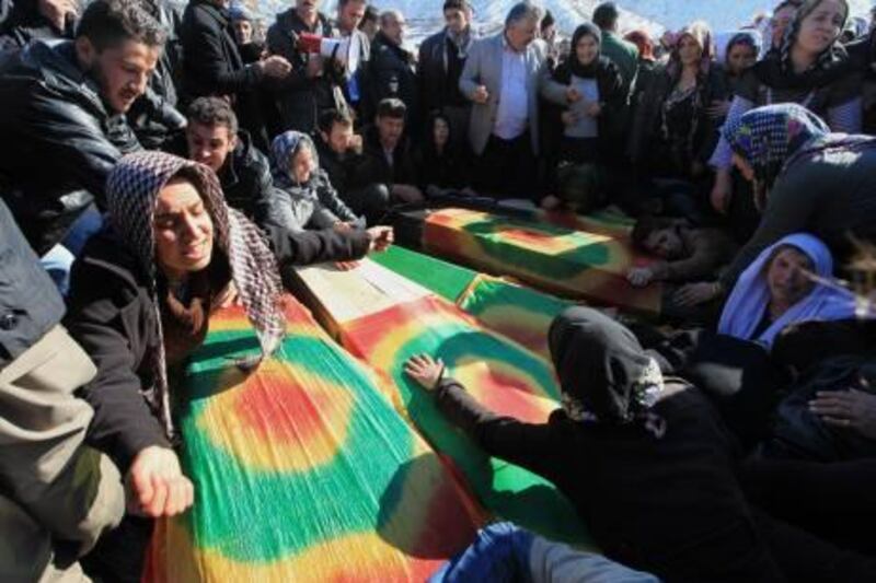 Family members cry over  the coffins of victims as thousands of mourners gathered in Gulyazi village at the border with Iraq, southeast Turkey, Friday, Dec. 30, 2011 for the funerals of 35 Kurdish civilians who were killed in a botched raid by Turkish military jets that mistook the group for Kurdish rebels based in Iraq. Turkish television footage showed people, many weeping and lamenting the dead, as they gathered after the air strikes Wednesday that killed a group of smugglers along the border, one of the deadliest episodes in the conflict between the Turkish state and Kurdish rebels who took up arms in 1984.(AP Photo)