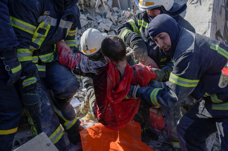 Rescuers carry a Ukrainian soldier saved after 30 hours from debris of the military school hit by Russian rockets in Mykolaiv. AFP