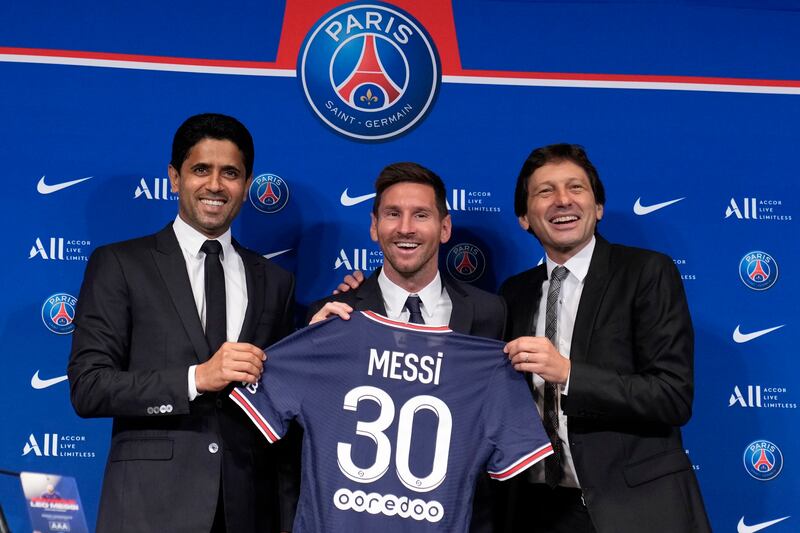 Lionel Messi poses with his jersey with PSG president Nasser Al-Khelaifi, left, and PSG sports director Leonardo.