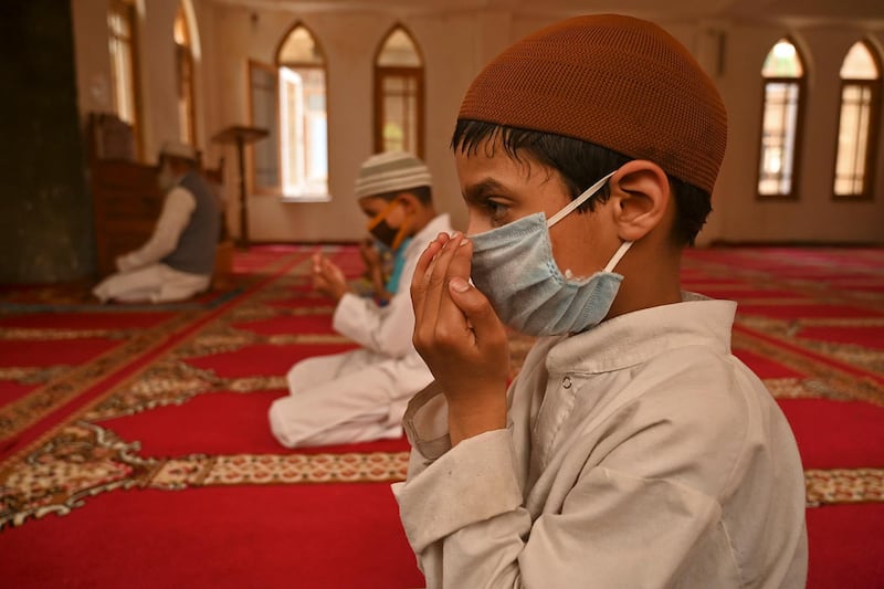 Muslim orphans wearing facemasks pray while maintaining social distancing inside a orphanage centre during the Muslim holy month of Ramadan in Srinagar on May 11, 2020. / AFP / Tauseef MUSTAFA
