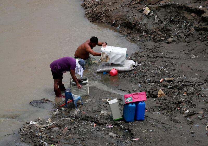 Filipino villagers clean belongings in a river after floods in the city of Marikina.  EPA