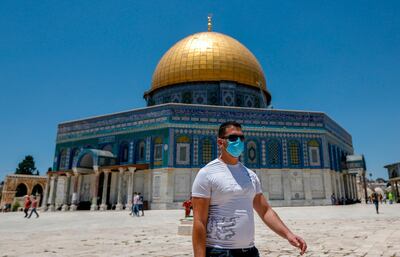 A Palestinian man, wearing a protective facemask, walks in front of the Dome of the Rock Mosque, in Jerusalem's Al-Aqsa mosques compound on July 3, 2020, during the novel coronavirus pandemic.  / AFP / AHMAD GHARABLI
