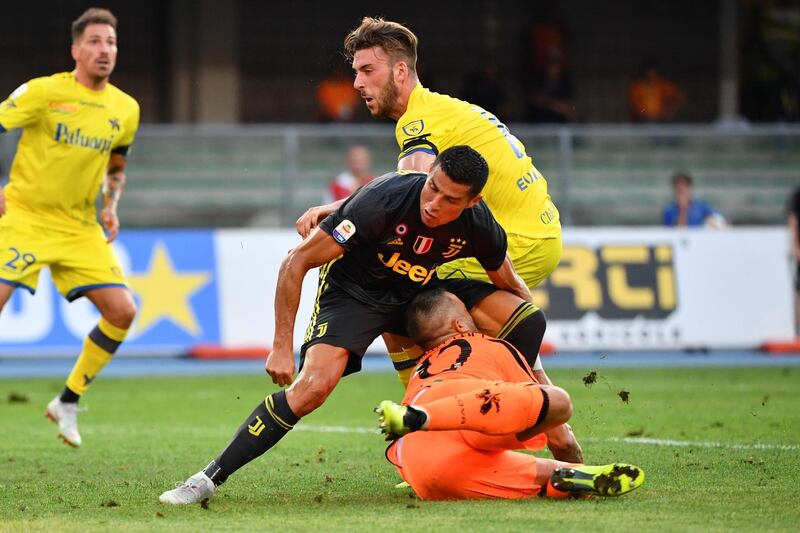 Juventus' Portuguese forward, Cristiano Ronaldo (C) collides with Chievo's goalkeeper Stefano Sorrentino (Bottom) during the Italian Serie A football match AC Chievo vs Juventus at the Marcantonio-Bentegodi stadium in Verona on August 18, 2018. (Photo by Alberto PIZZOLI / AFP)