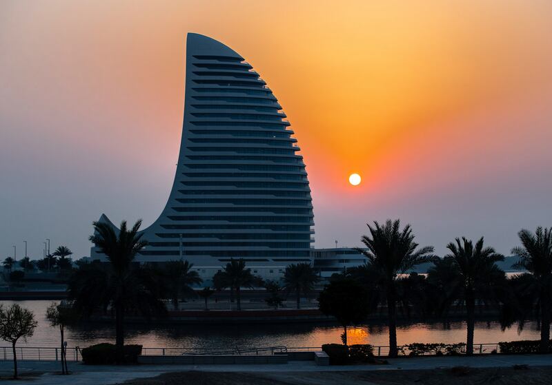 The sun sets behind the Al Sail Tower on Al Raha Creek, Abu Dhabi. Victor Besa / The National