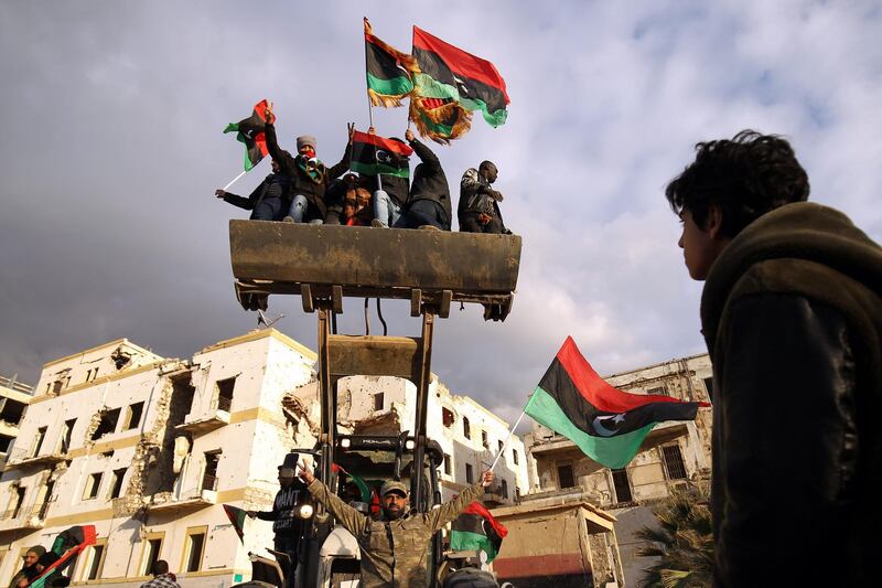 Libyan men on a bulldozer wave the national flag as they gather to mark the eighth anniversary of the uprising in Libya's second city of Benghazi. AFP