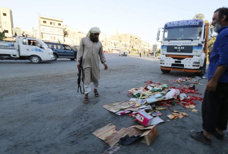 An Islamic State fighter keeps guard as people, who according to him are employees of the Islamic State hired to monitor and check the quality of goods in markets, throw confiscated products on the ground in central Raqqa on August 14. Reuters