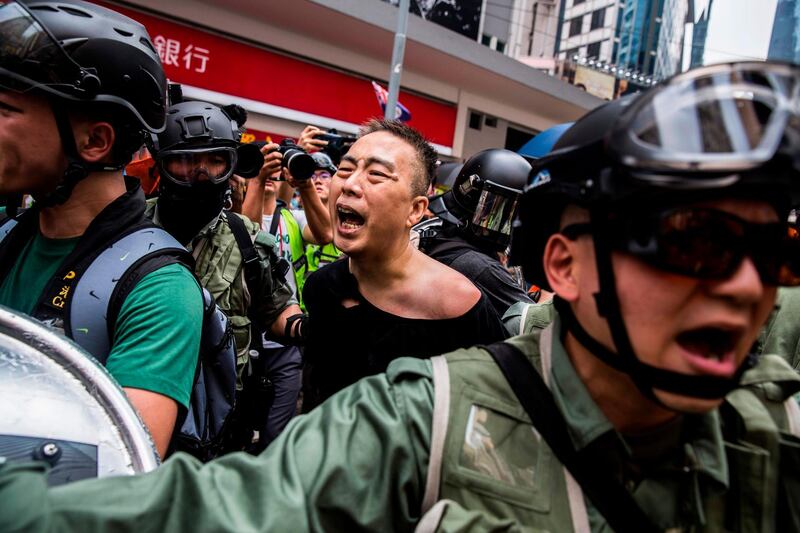 Police detain a man  for questioning as people gather in the Causeway Bay shopping district in Hong Kong. AFP