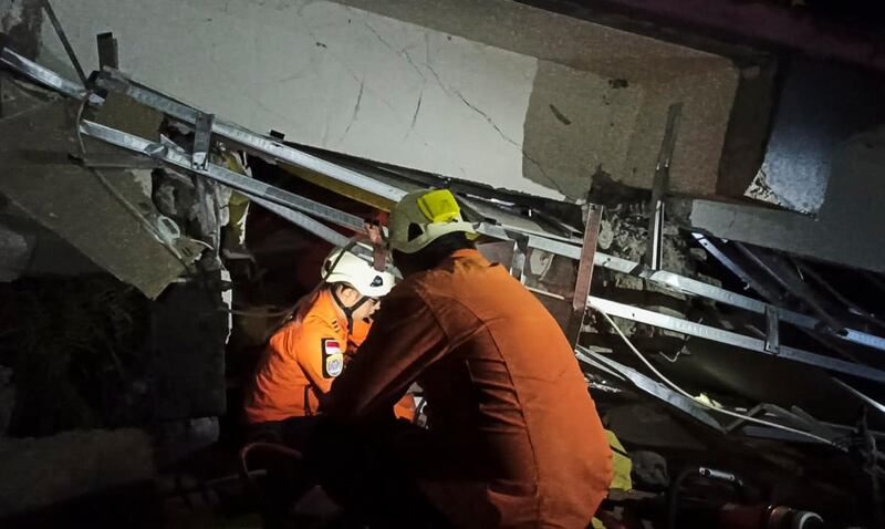 Rescuers search for victims under the rubble of a collapsed building in Mamuju. BASARNAS / EPA